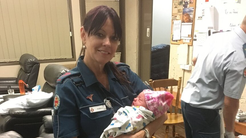 QAS officer holds newborn girl.