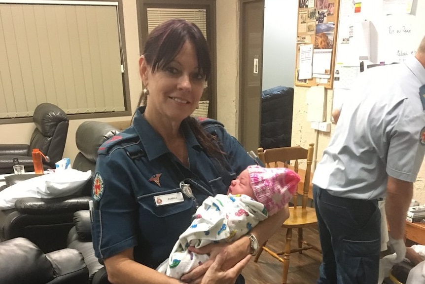 QAS officer holds newborn girl.