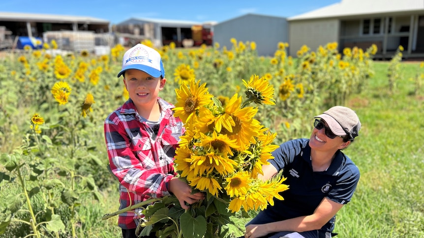 A 7-year-old boy holds a large bunch of sunflowers