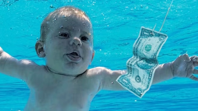 A baby swimming towards a dollar bill.