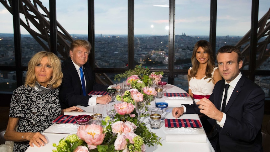 Donald and Melania Trump and Emmanuel and Brigitte Macron smile for a photo while sitting at a table in the Eiffel Tower.