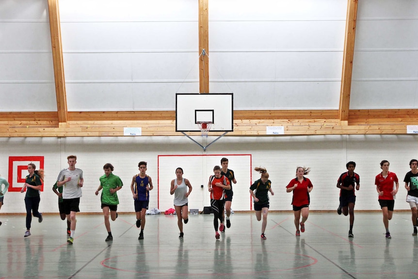 A line of students running across a basketball court