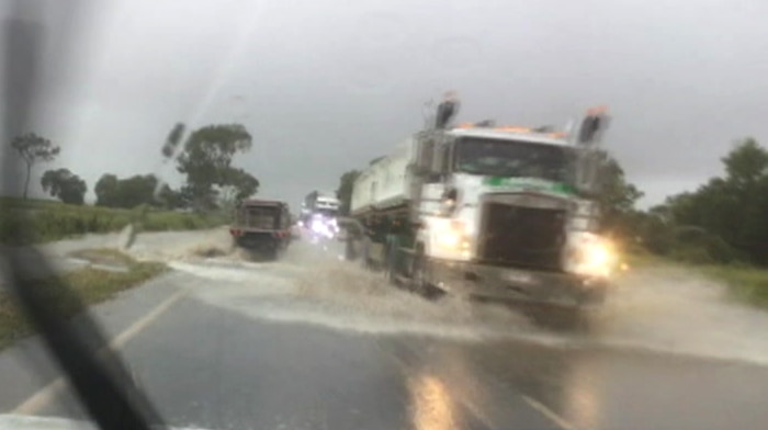 Trucks and cars drive through water on the Bruce Highway.