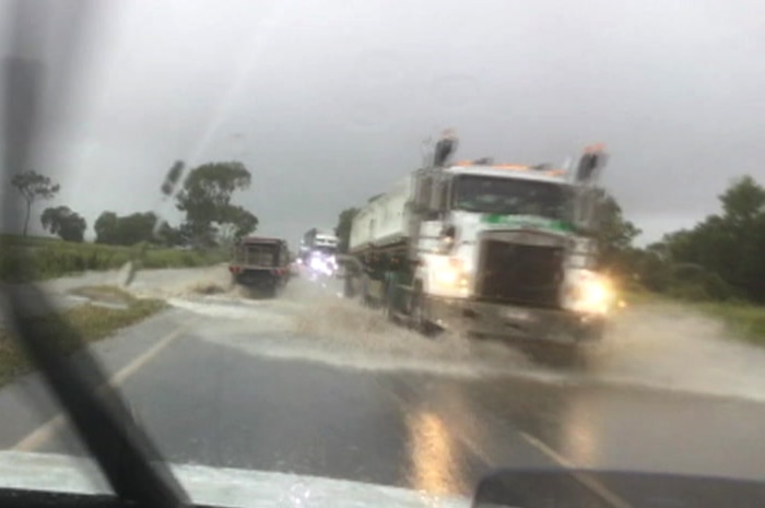 Trucks and cars drive through water on the Bruce Highway.
