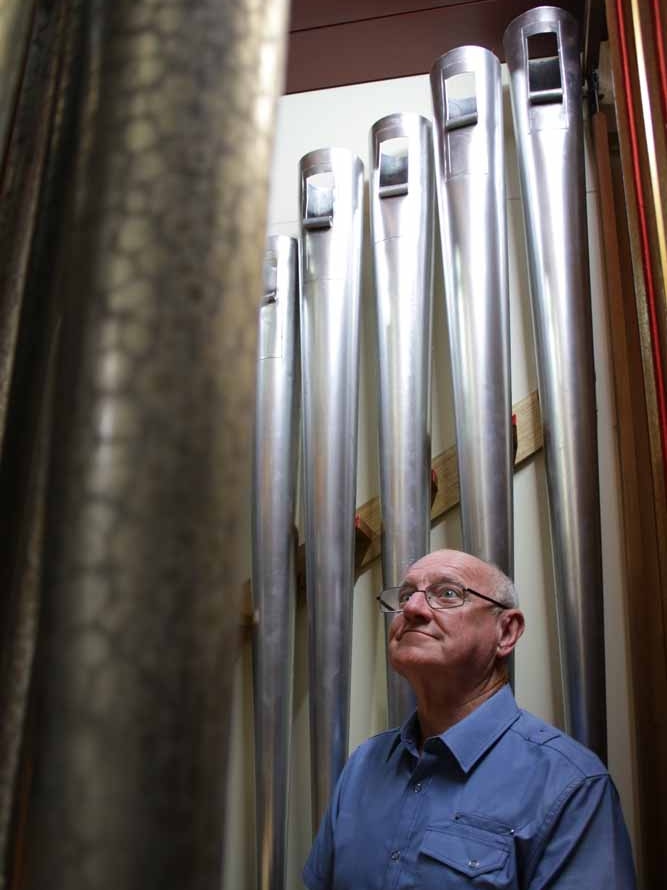 Man standing among church organ pipes