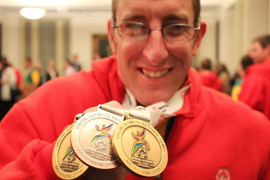Tim Beattie holding his three medals from the 2014 Special Olympics in Melbourne.