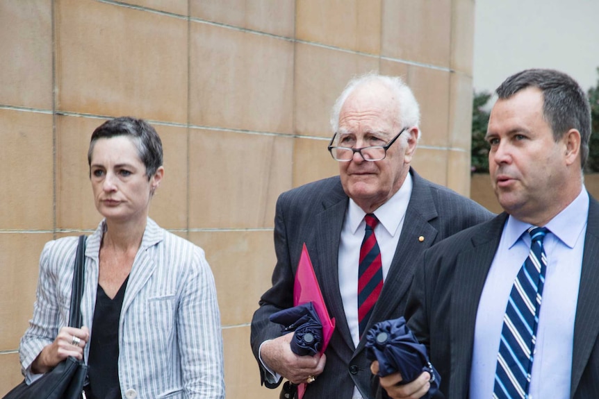Former Governor General Peter Hollingworth in Hobart flanked by legal counsel.