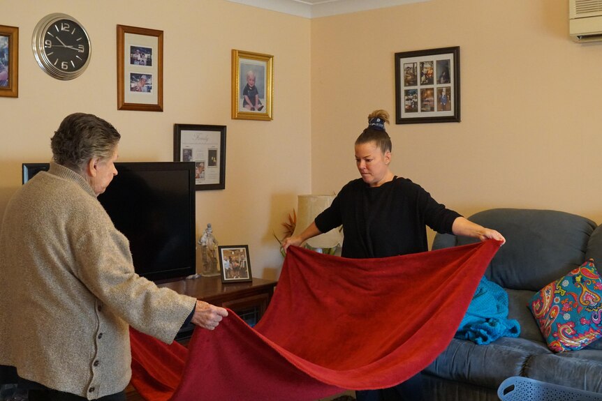 A woman and her elderly mother folding a blanket.