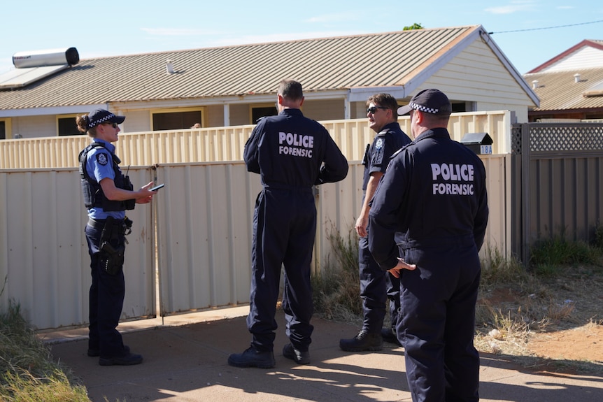 Police forensic officers at a gate to a house in Carnarvon.