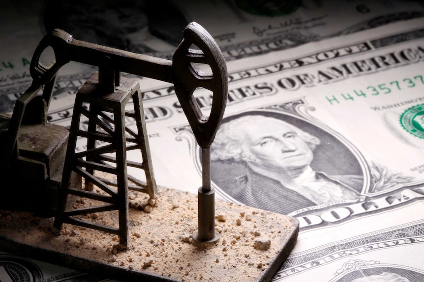 A 3D printed oil pump jack is placed on dollar banknotes in this illustration picture