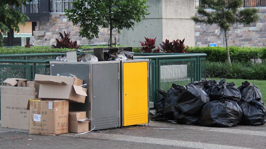 Rubbish left over from New Year's Eve celebrations at South Bank in Brisbane is stacked in and around two council bins.