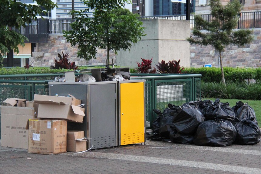 Rubbish left over from New Year's Eve celebrations at South Bank in Brisbane is stacked in and around two council bins.