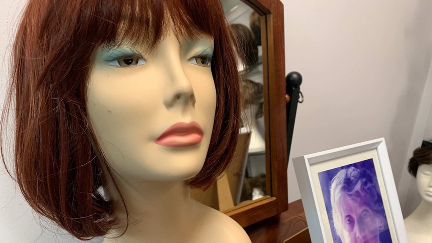 A wig on model next to a framed photo of an older woman