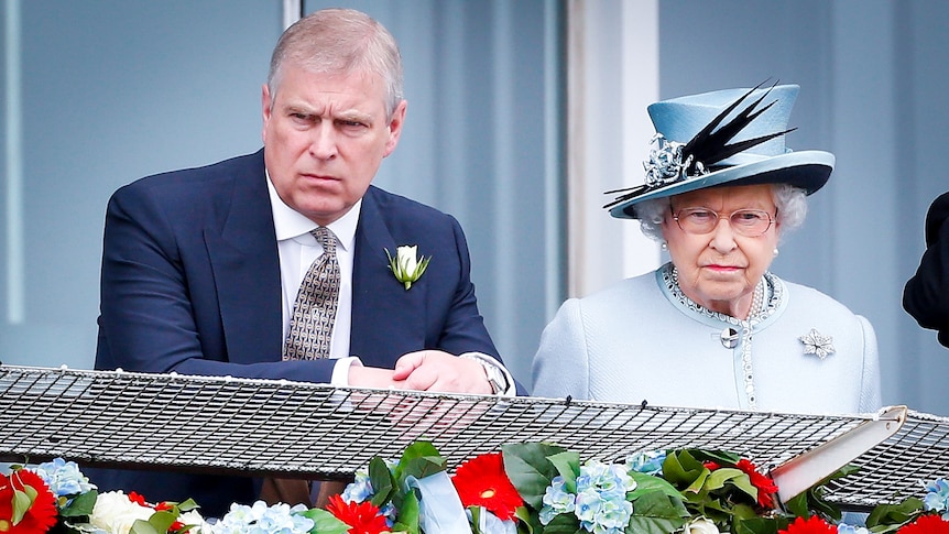 Prince Andrew and Queen Elizabeth looking serious as they stand at a balcony decorated with flowers