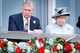 Prince Andrew and Queen Elizabeth looking serious as they stand at a balcony decorated with flowers