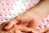 An elderly person's hand is held by a younger person.