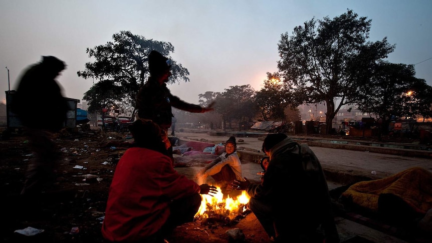 Indian homeless sit around a fire on a cold morning in an old quarter of New Delhi