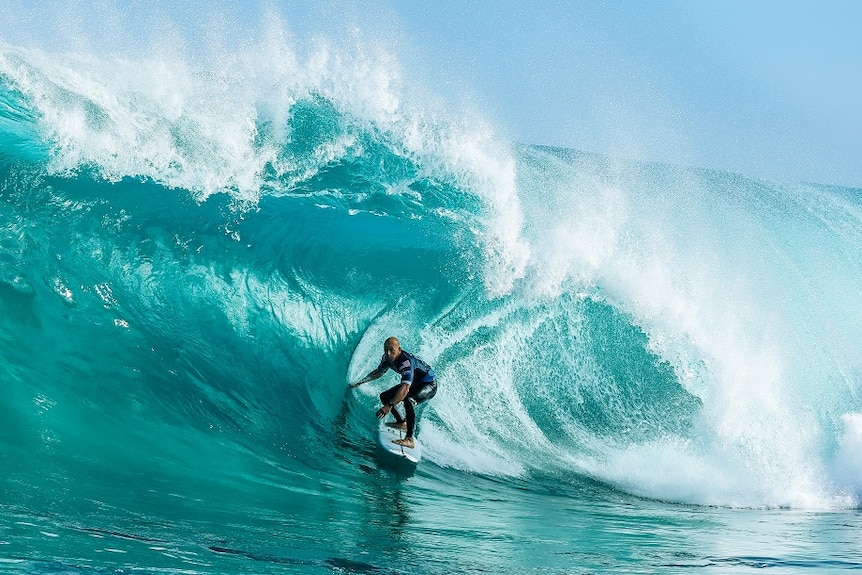 Kelly Slater rides a big wave tube.