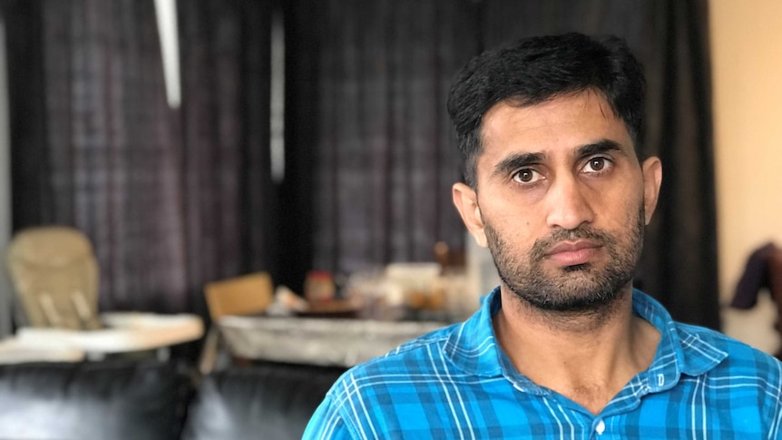 Yasir Amin standing in a blue shirt looking at camera.