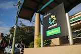 A large centrelink sign with two men walking past in the background