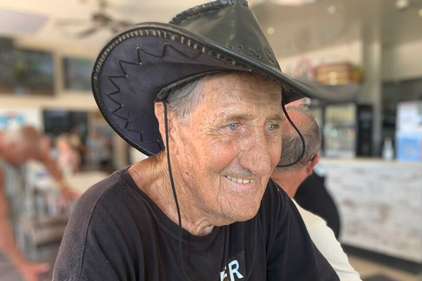 A man wearing an Akubra-style hat smiles in a bar.