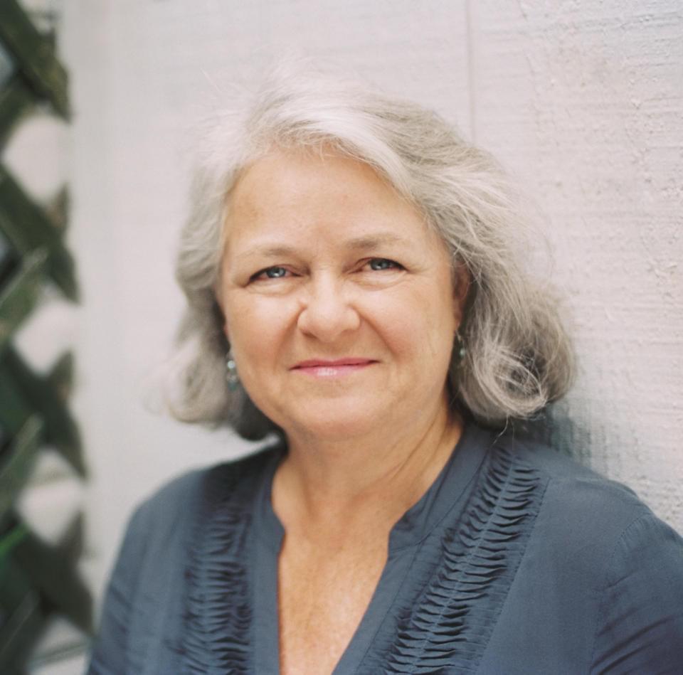 Profile photograph of a smiling woman with medium-length grey hair.