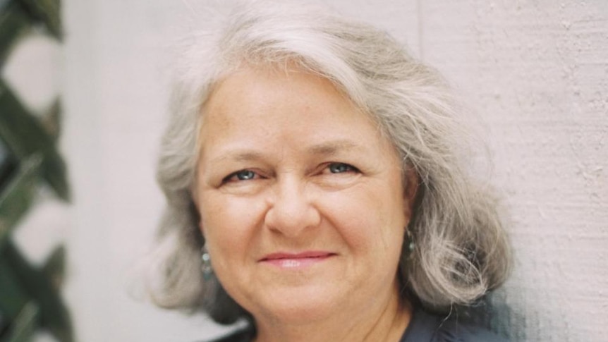Profile photograph of a smiling woman with medium-length grey hair.