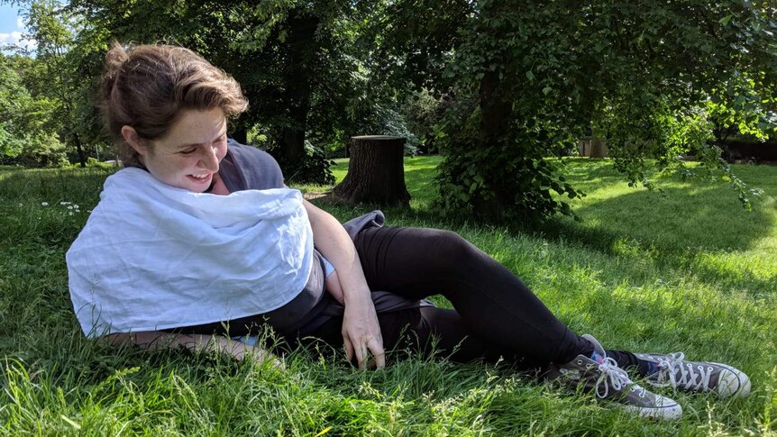 Olivia Humphreys lying on the grass outside with her baby, Kit.