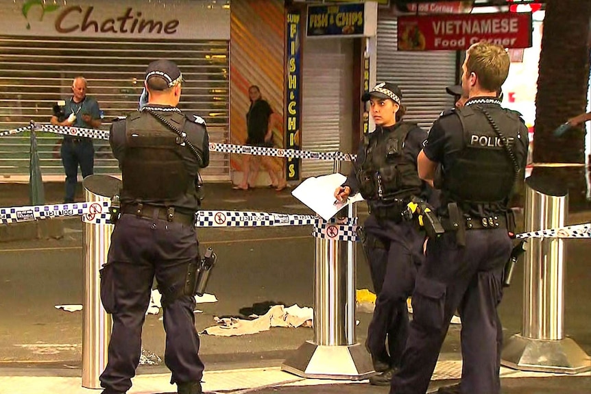 Police standing near a crime scene marked with police tape