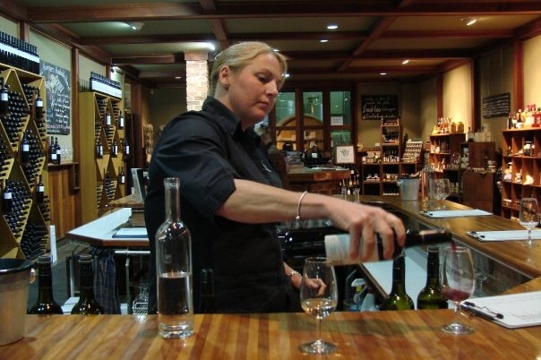Cellar door staff pours wine into glass for tasting.