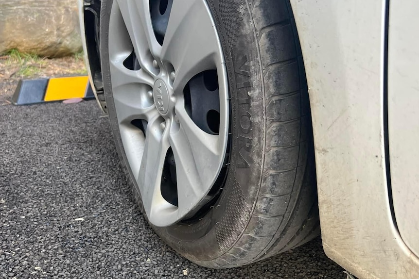 A close up of a black tyre with dented rim.