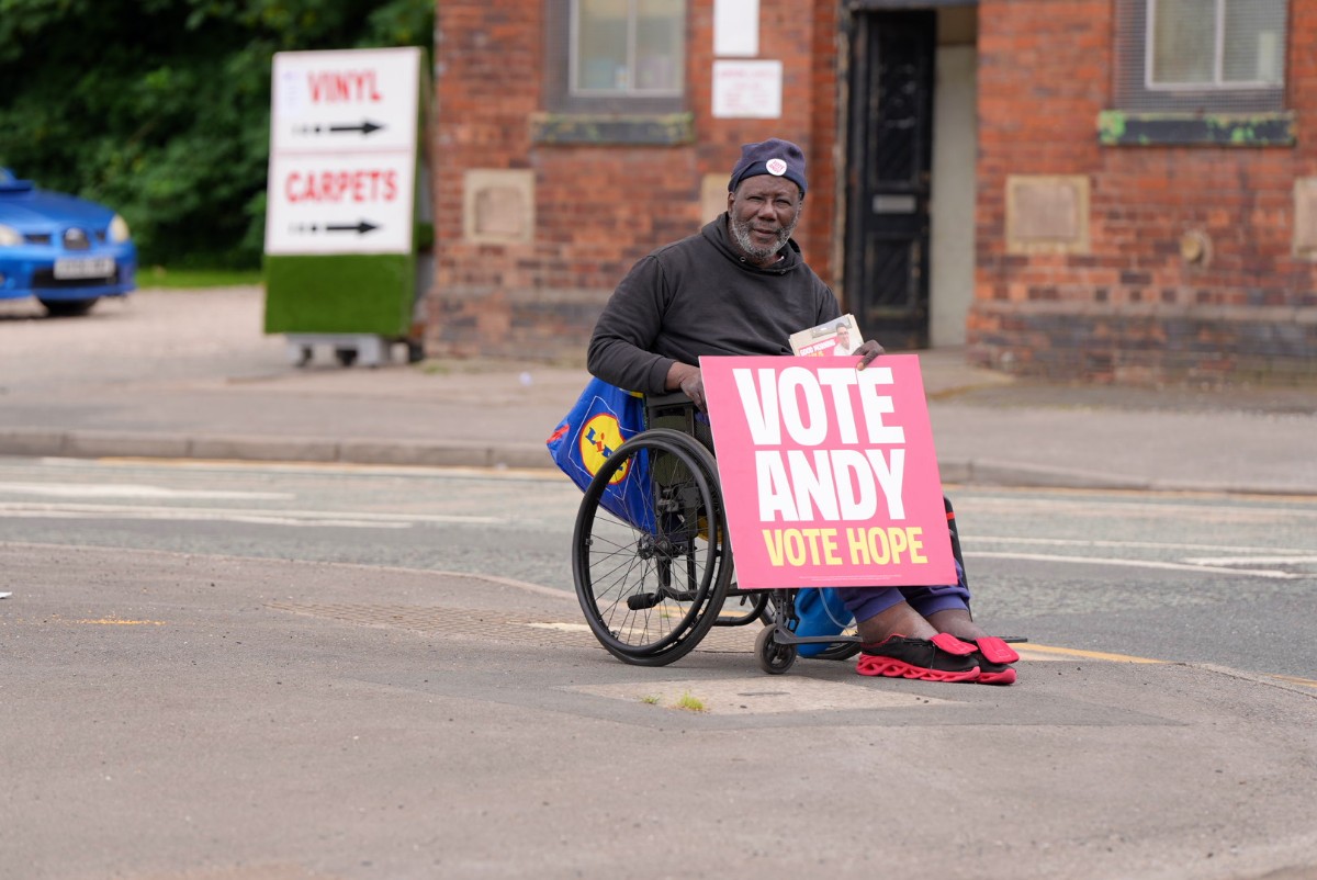 A man sitting in a wheelchair, holding a sign that says Vote Andy For Hope on it.