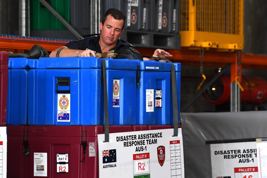 A Fire and Rescue officer loads disaster response equipment at a facility in Brisbane