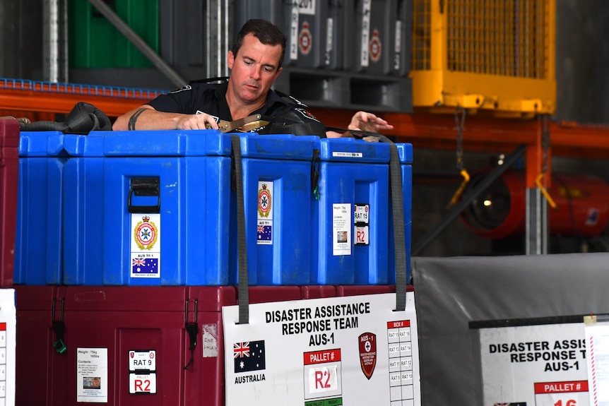 A Fire and Rescue officer loads disaster response equipment at a facility in Brisbane