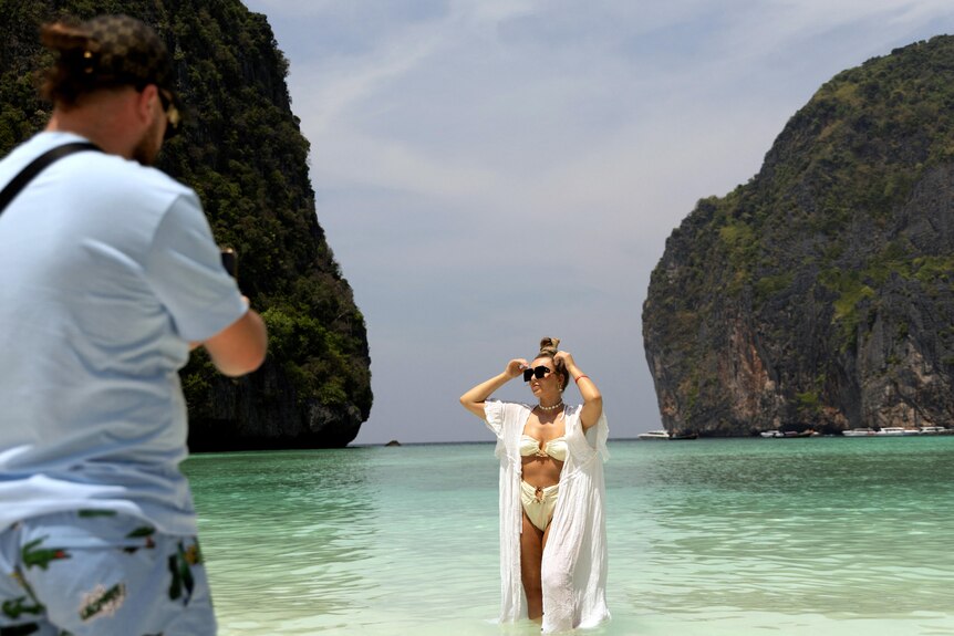 A man taking a photo of a woman standing in a bay