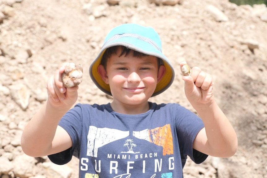 Nine-year-old boy Kaleb holds up two thundereggs he unearthed.