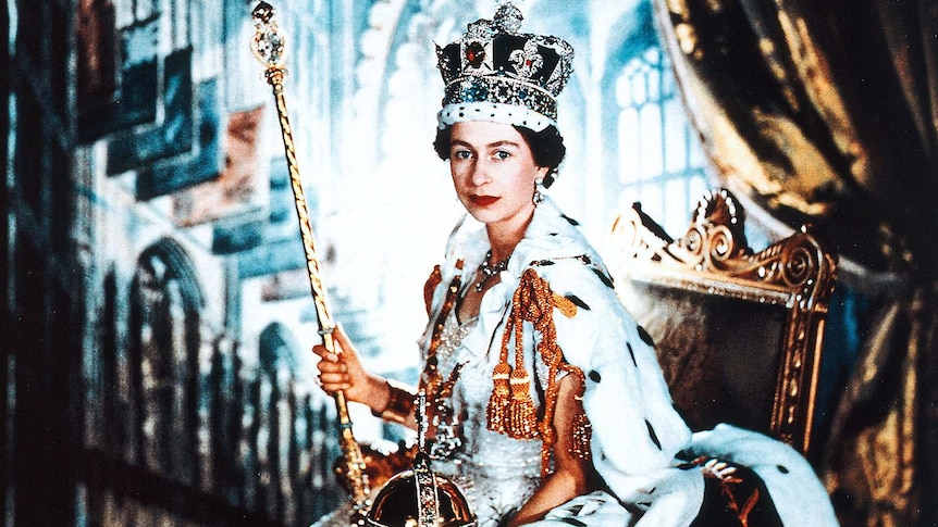 Queen Elizabeth poses in her coronation dress and robe and wearing the Imperial State Crown while holding the Sceptre and Orb.