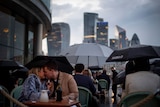 A couple kiss among other patrons holding umbrellas at a restaurant in London