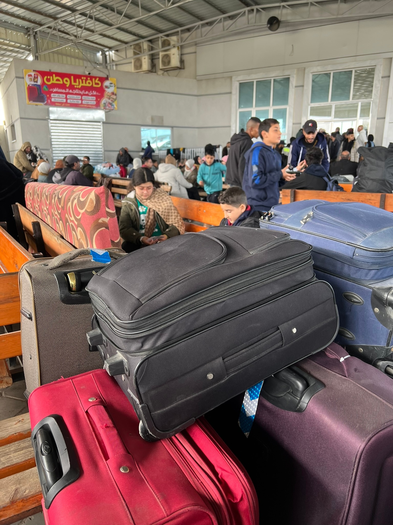 People waiting in a room with suitcases.