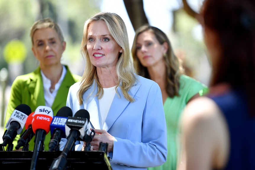 a woman talking into microphones at a press conference