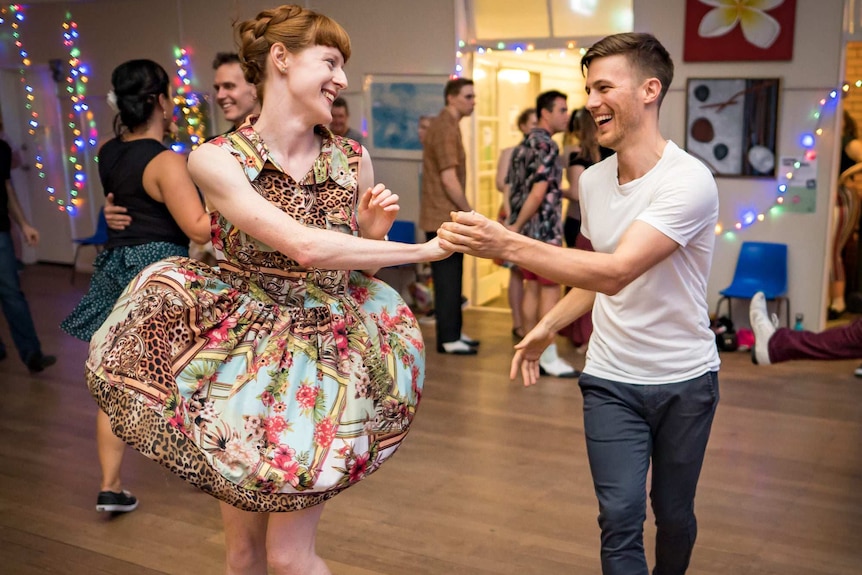 A couple dance in a socially distanced room.