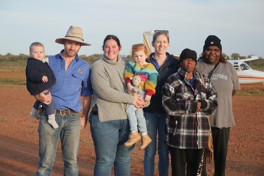 A family and visitors standing in front of a plane in outback NSW.
