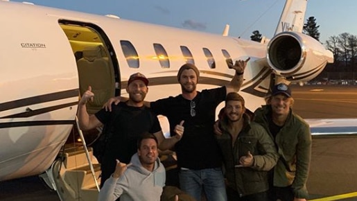 Chris Hemsworth with group of men outside a plane.