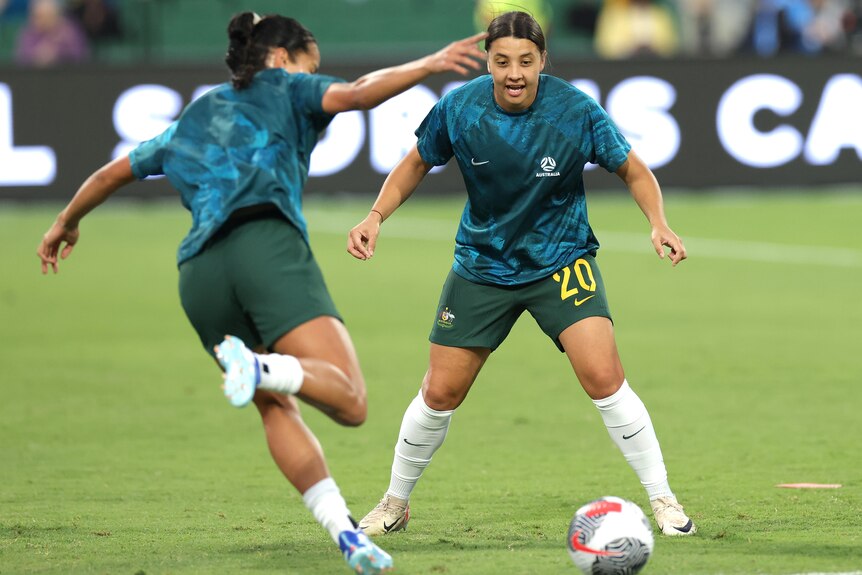 Two women training on a soccer pitch.