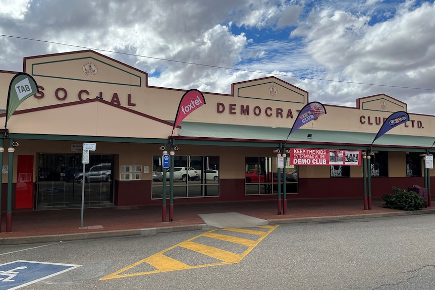 The front of a building with banners and signs flying behind an empty street