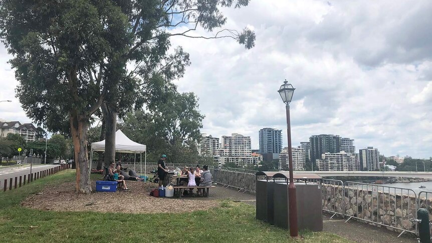 Storm clouds gather as families secure a spot on Brisbane's Kangaroo Point cliffs for NYE fireworks on December 31, 2017.
