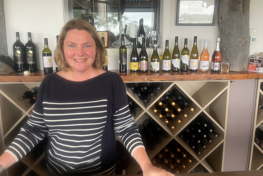 Woman standing in front of wine rack.