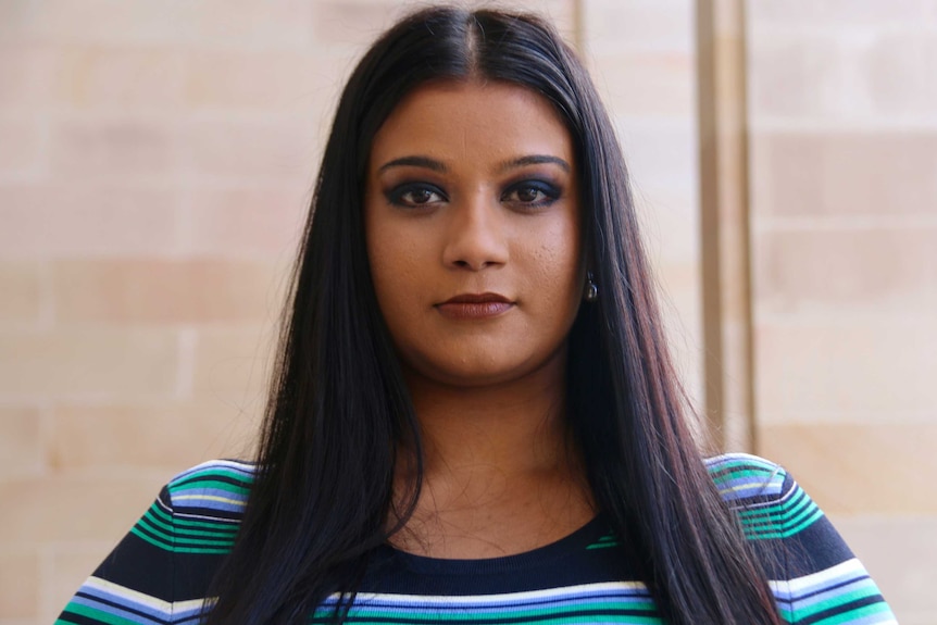 A head and shoulders shot of a woman standing on the front steps of Parliament House.