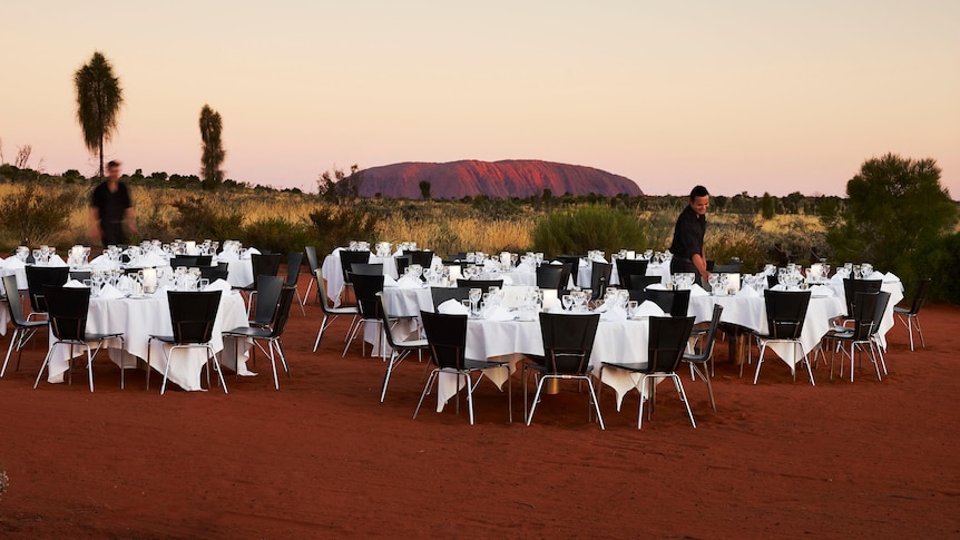 A dinner setting in front of Uluru at dusk