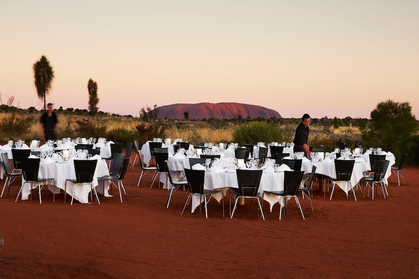 A dinner setting in front of Uluru at dusk